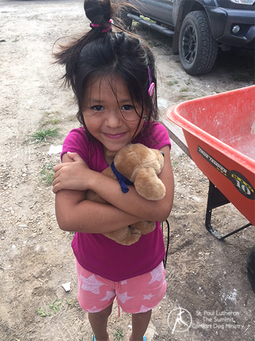 Little girl in pink hugging a Phoebe Jr. tightly after floods in TX. She now wears a smile.